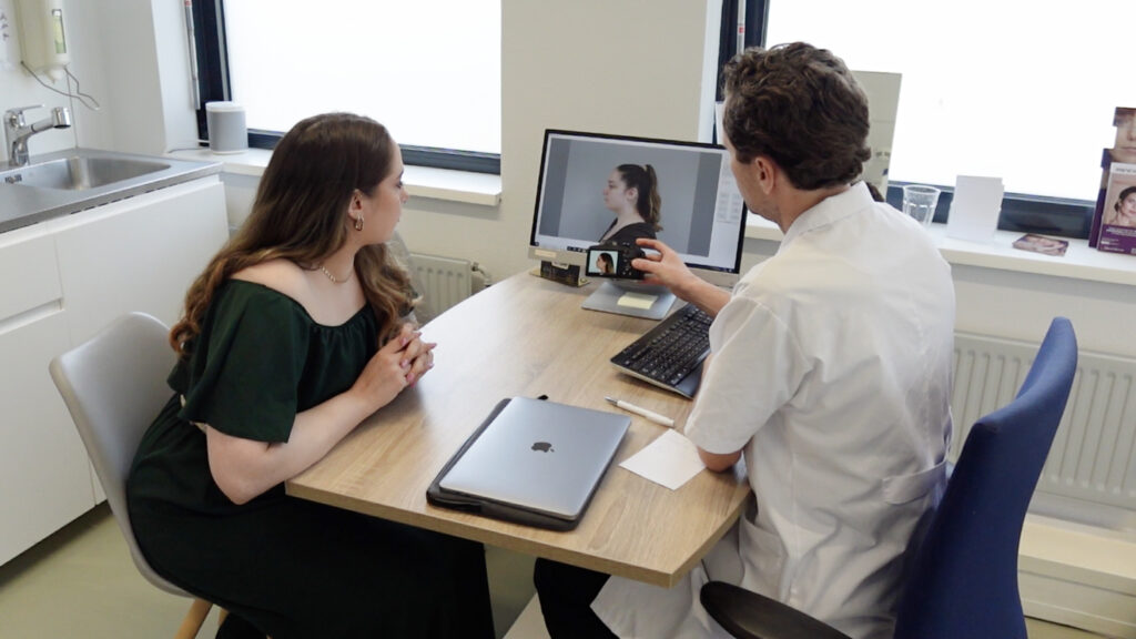 Arts bespreekt fotos van de kaaklijn met een client tijdens het consult